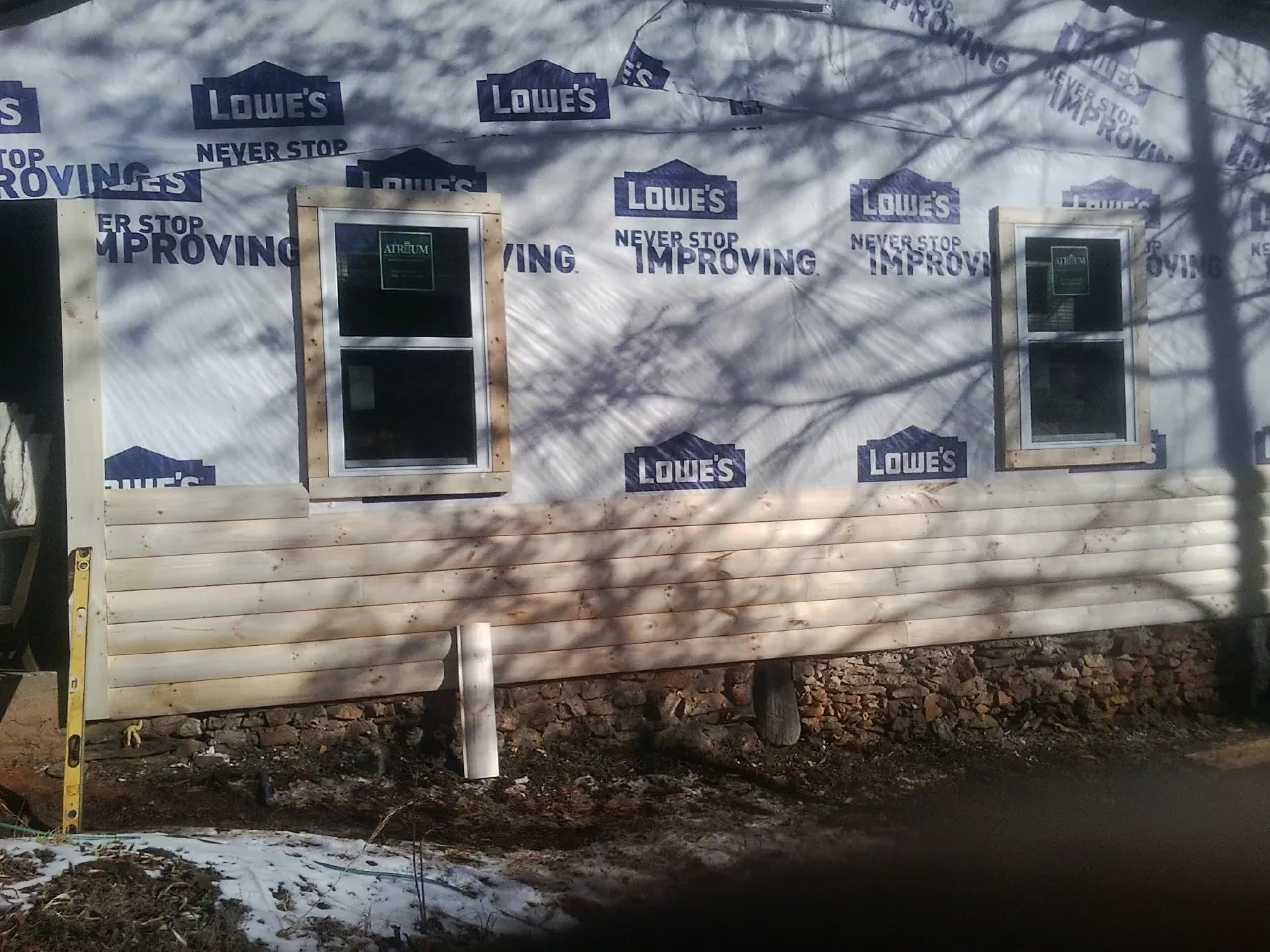House wrap and new log siding going up on an exterior wall in Wellsville